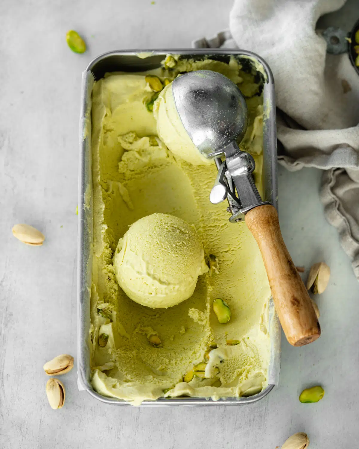 vegan pistachio ice cream in a metal container with vintage ice cream scoop.