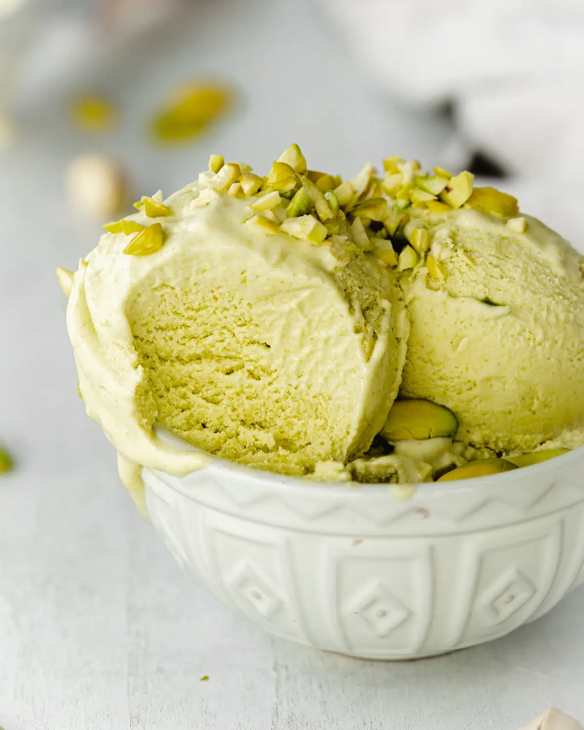 close up of pistachio ice cream with chopped pistachios in a porcelain ramekin.