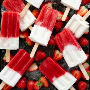 strawberry and yogurt popsicles on a tray with fresh strawberries and ice.
