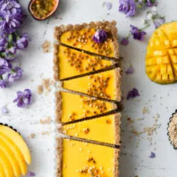 flatlay of rectangular mango tart with purple flowers.