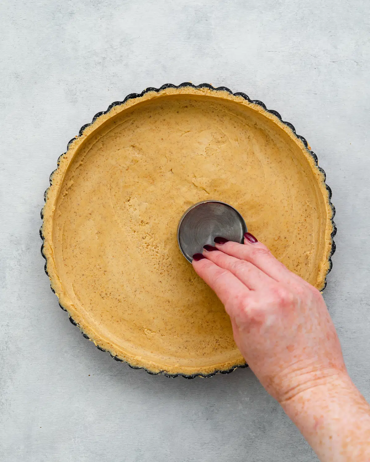 smoothing out pastry with a cup measure.