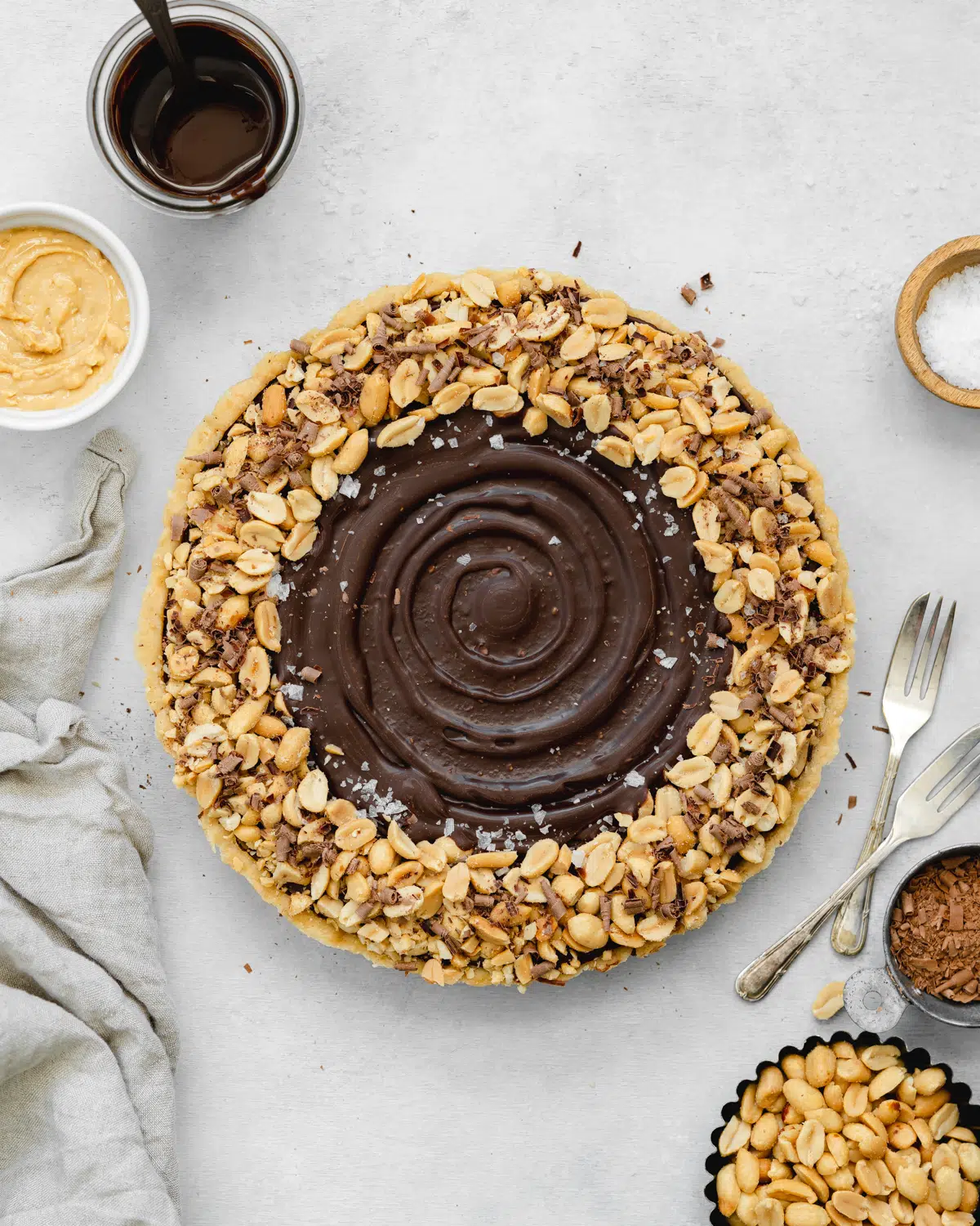 chocolate tart with roasted peanuts on a grey surface.