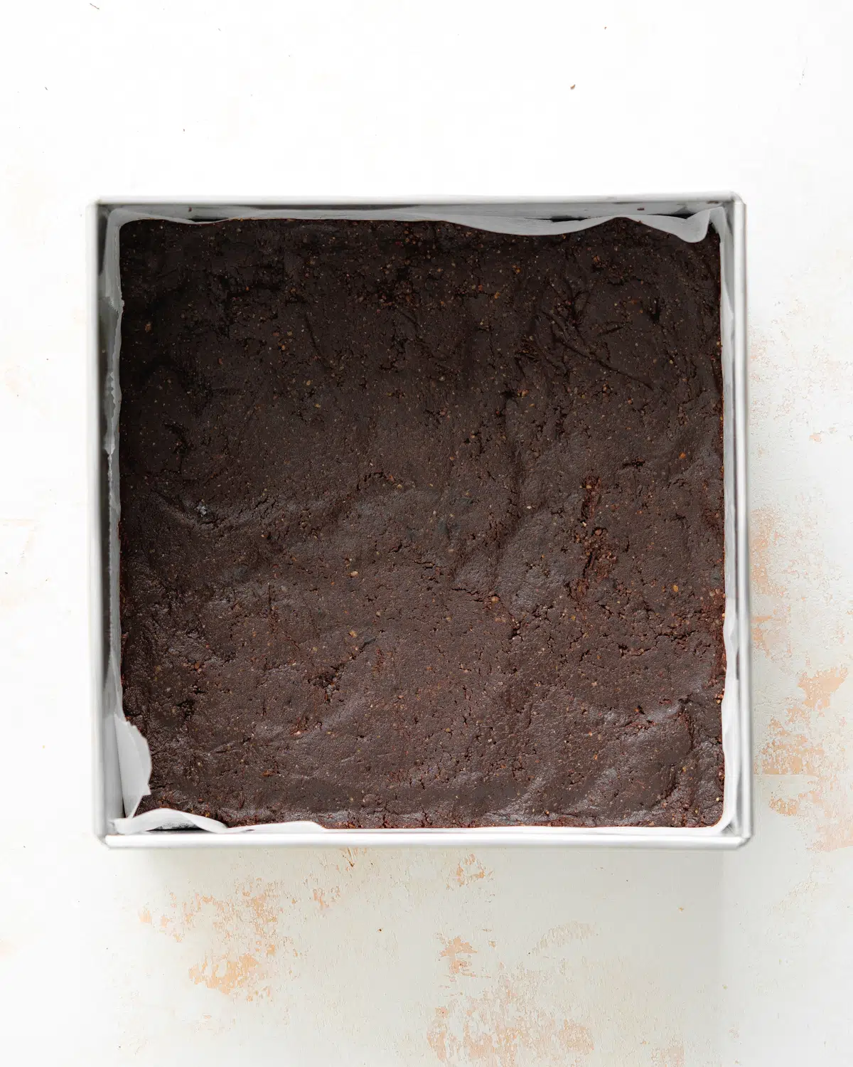 pressing brownie dough into cake pan.