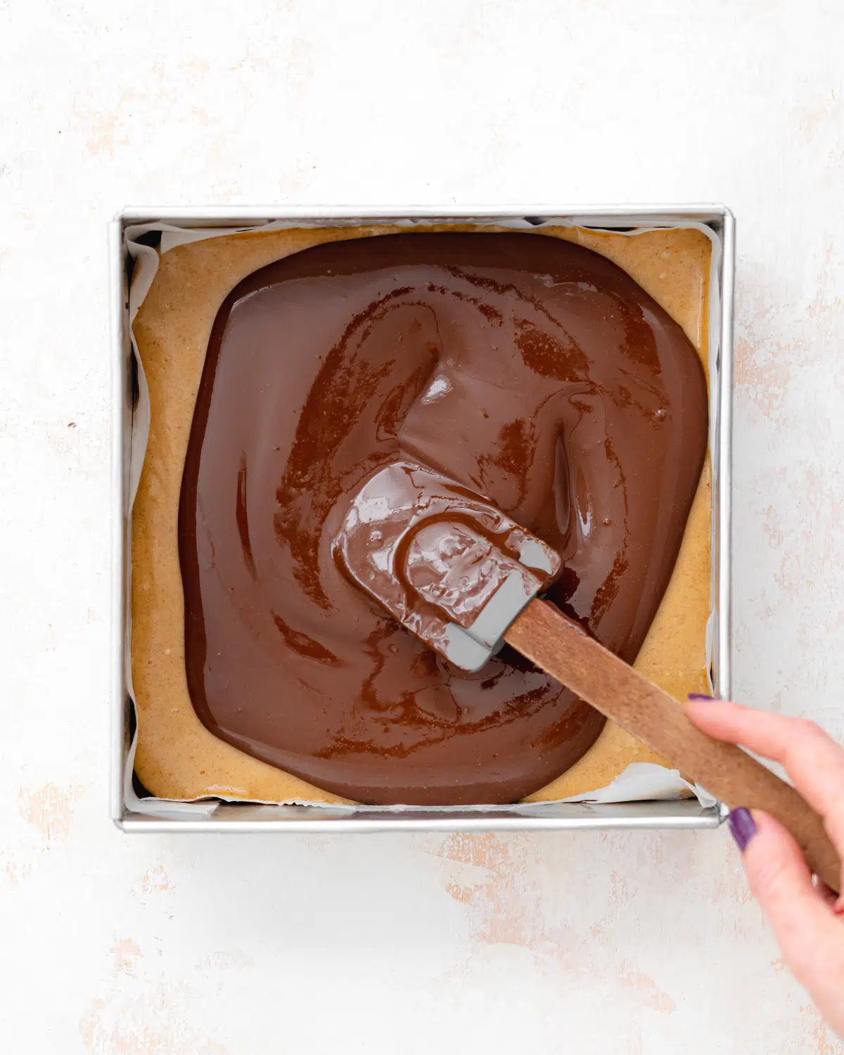 covering vegan caramel brownies with chocolate.