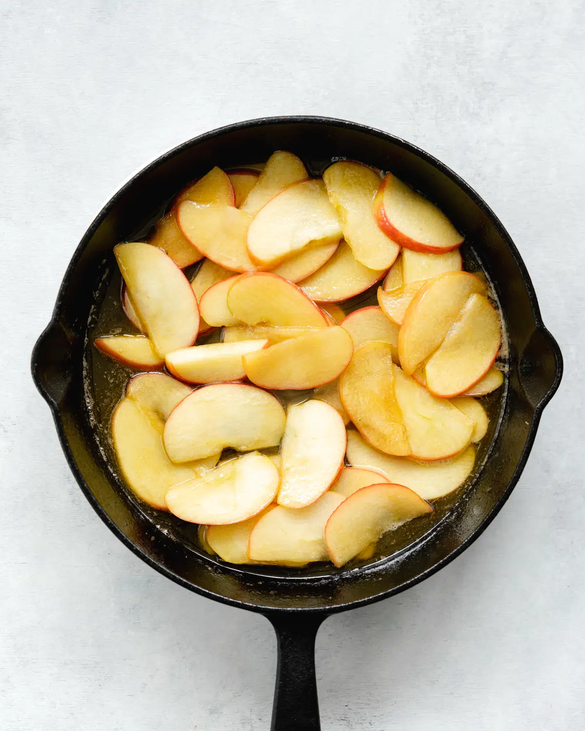 apple slices in a skillet with sugar and butter.