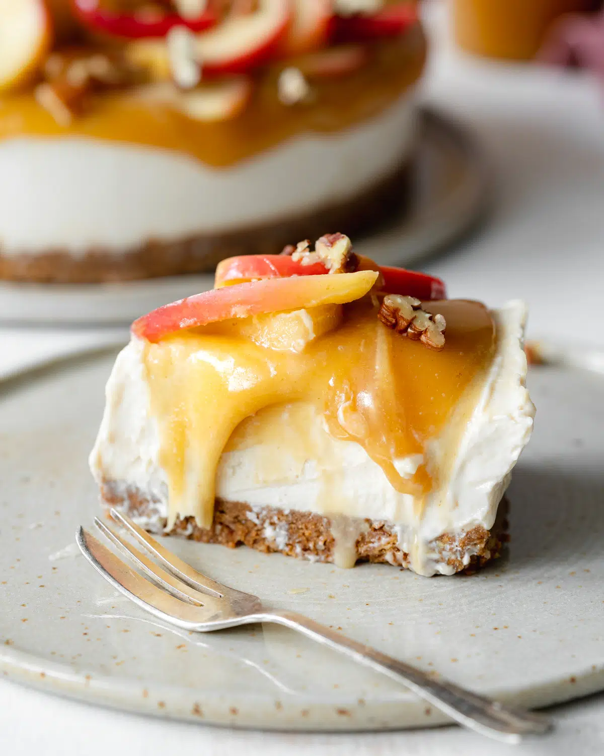 slice of vegan cheesecake with caramel and apples on top.