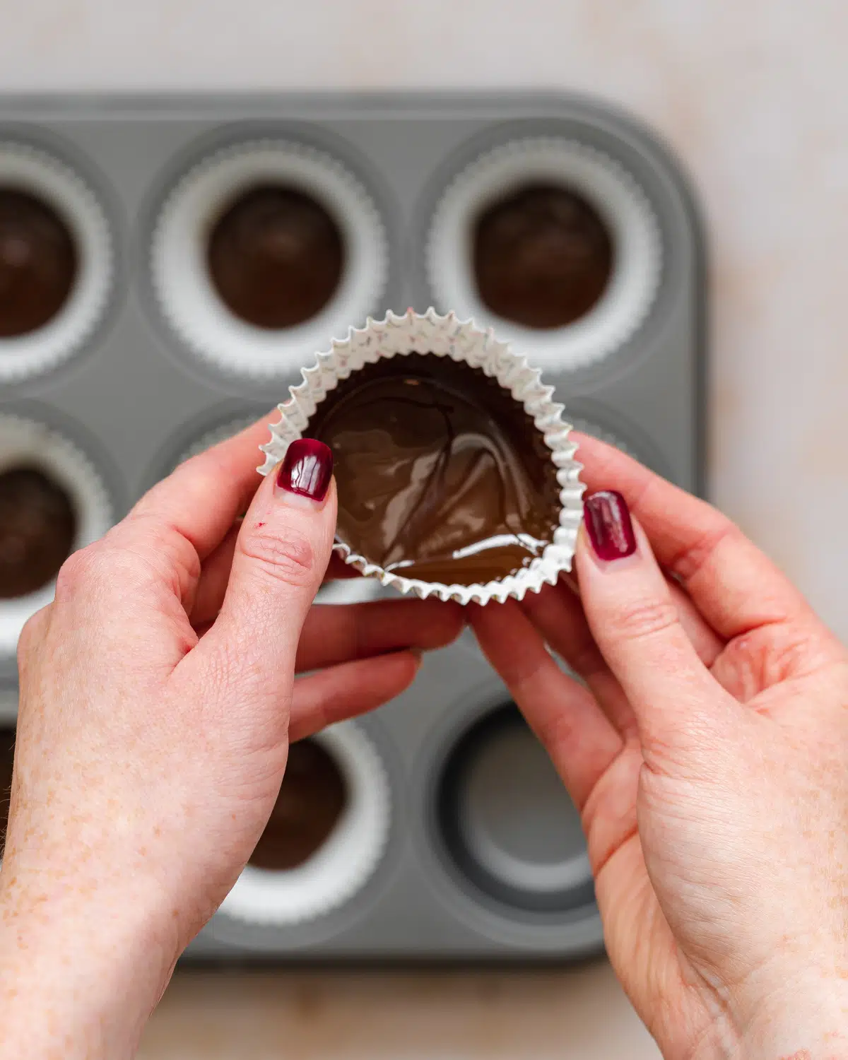 adding chocolate to muffin cases for peanut butter cups.