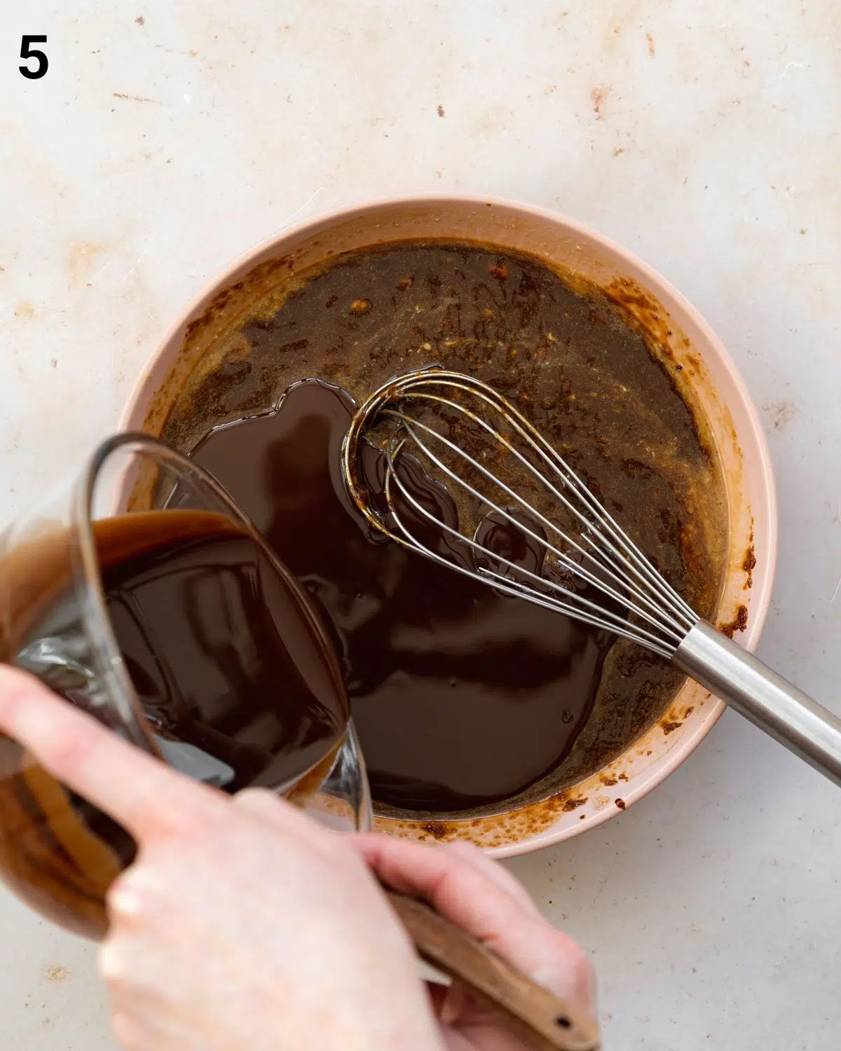whisking brownie batter in a bowl.