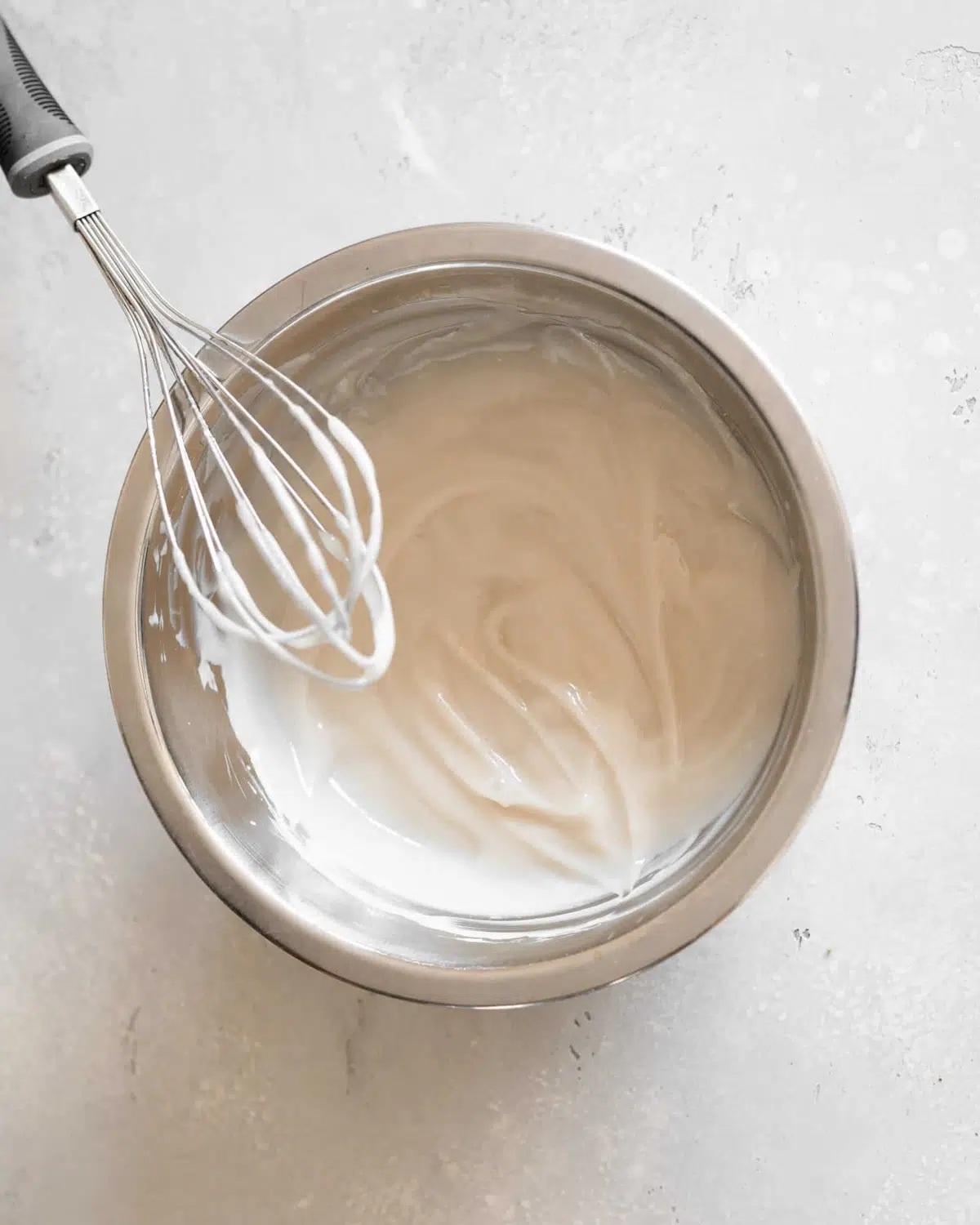 dairy free condensed milk in a bowl with a whisk.