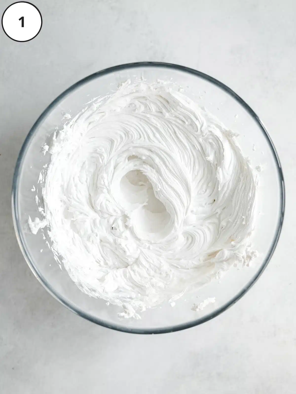 top down view of whipped coconut cream in a clear bowl.