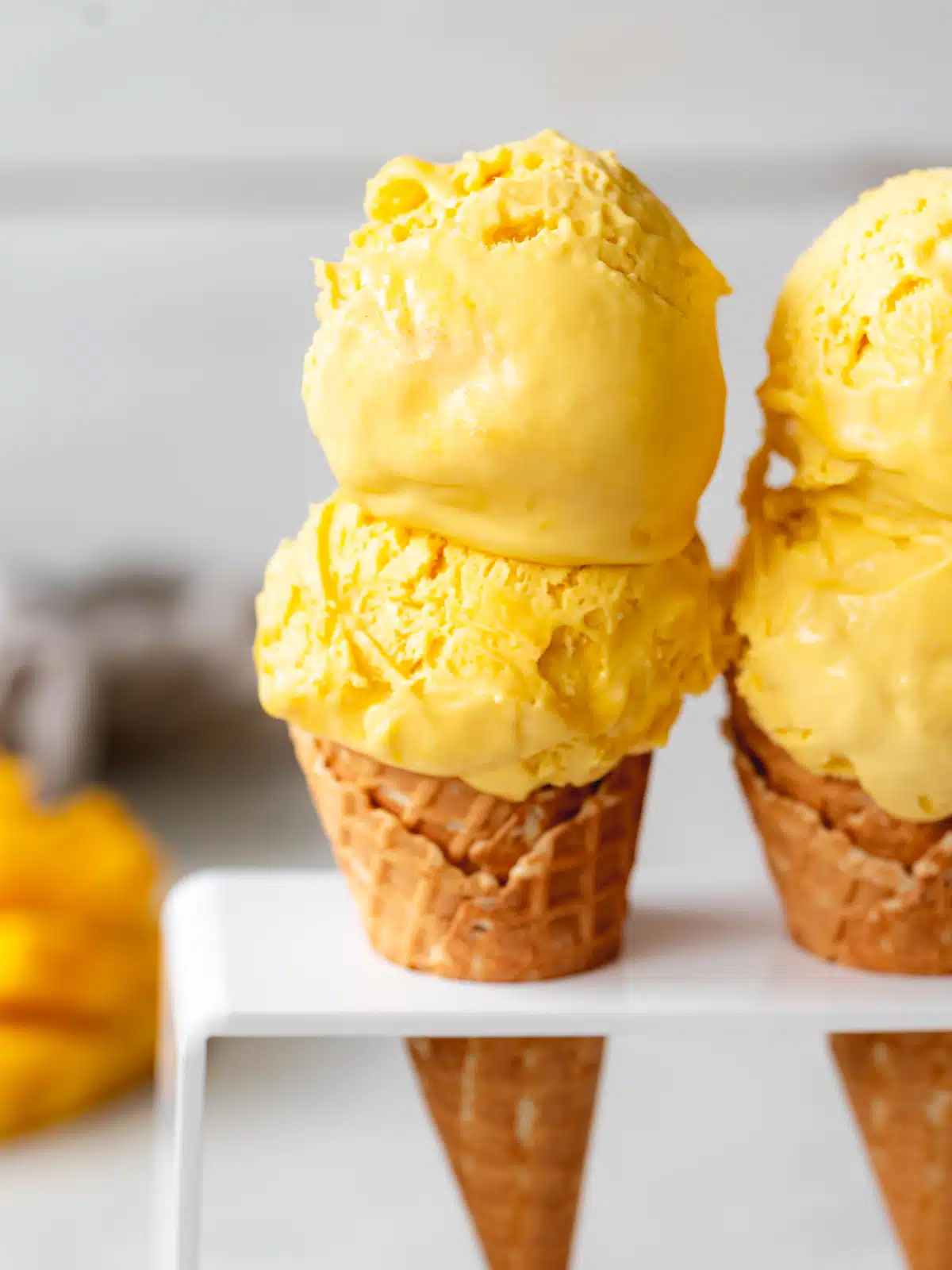 close up of two ice cream cones with scoops of mango ice cream