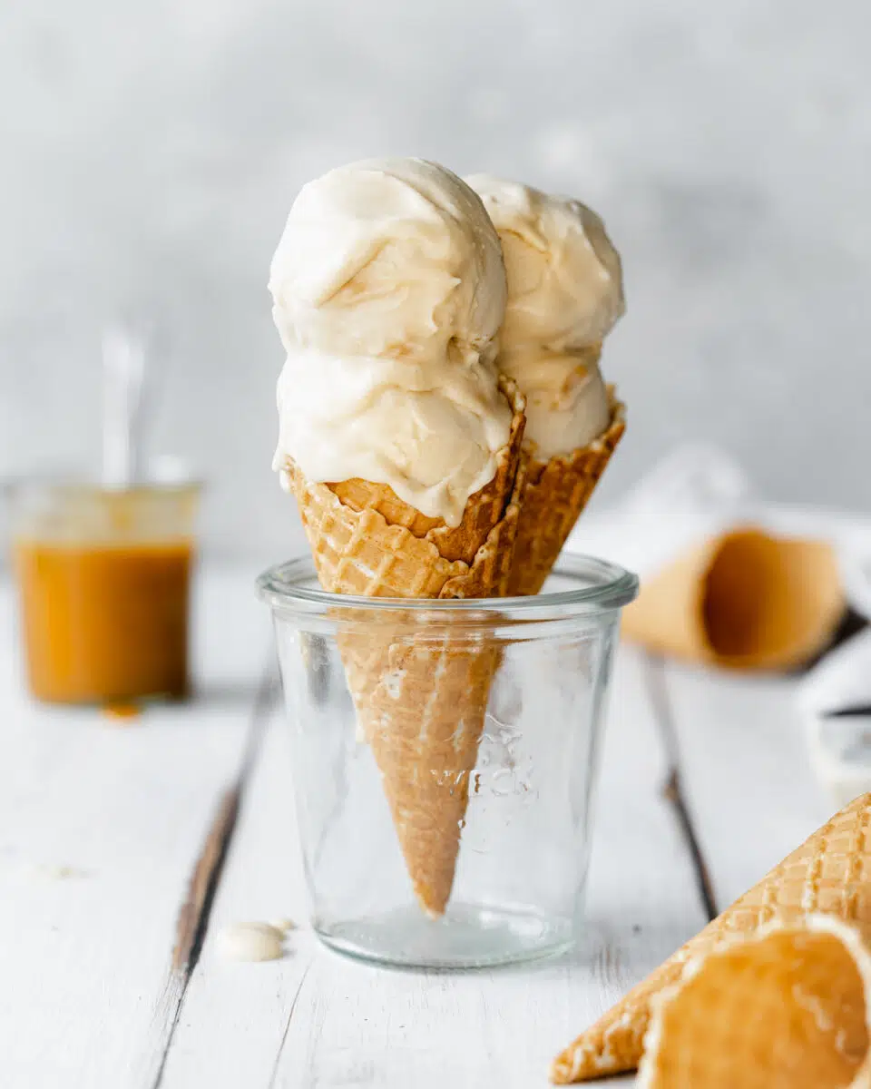 2 salted caramel ice cream cones in a glass with grey background.
