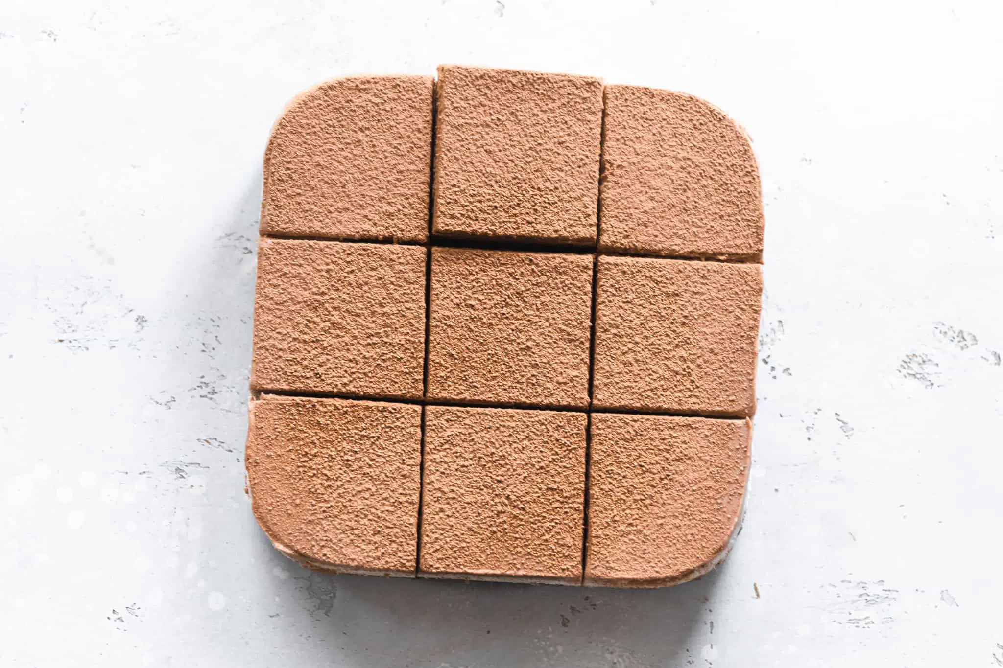 Flaylay of vegan chai latter cheesecake cut into cubes on grey stone surface