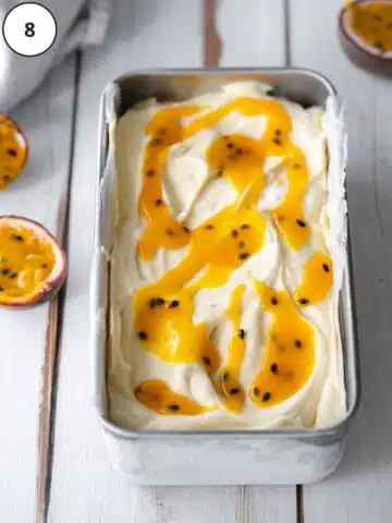 vegan passion fruit ice cream with passion fruit puree swirled on top in a loaf pan, fresh from the freezer.