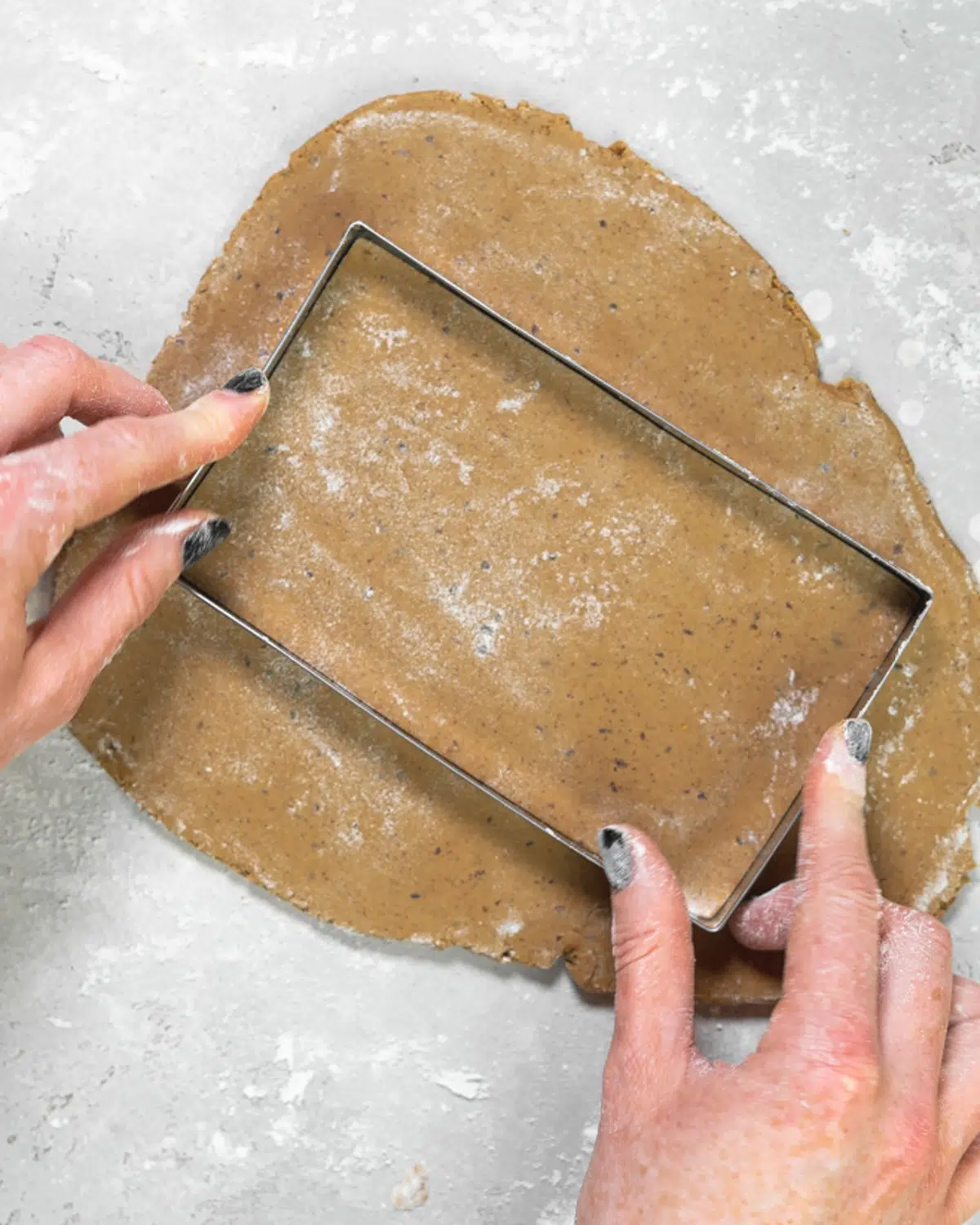 rectangular cookie cutter on top of rolled out gingerbread dough.