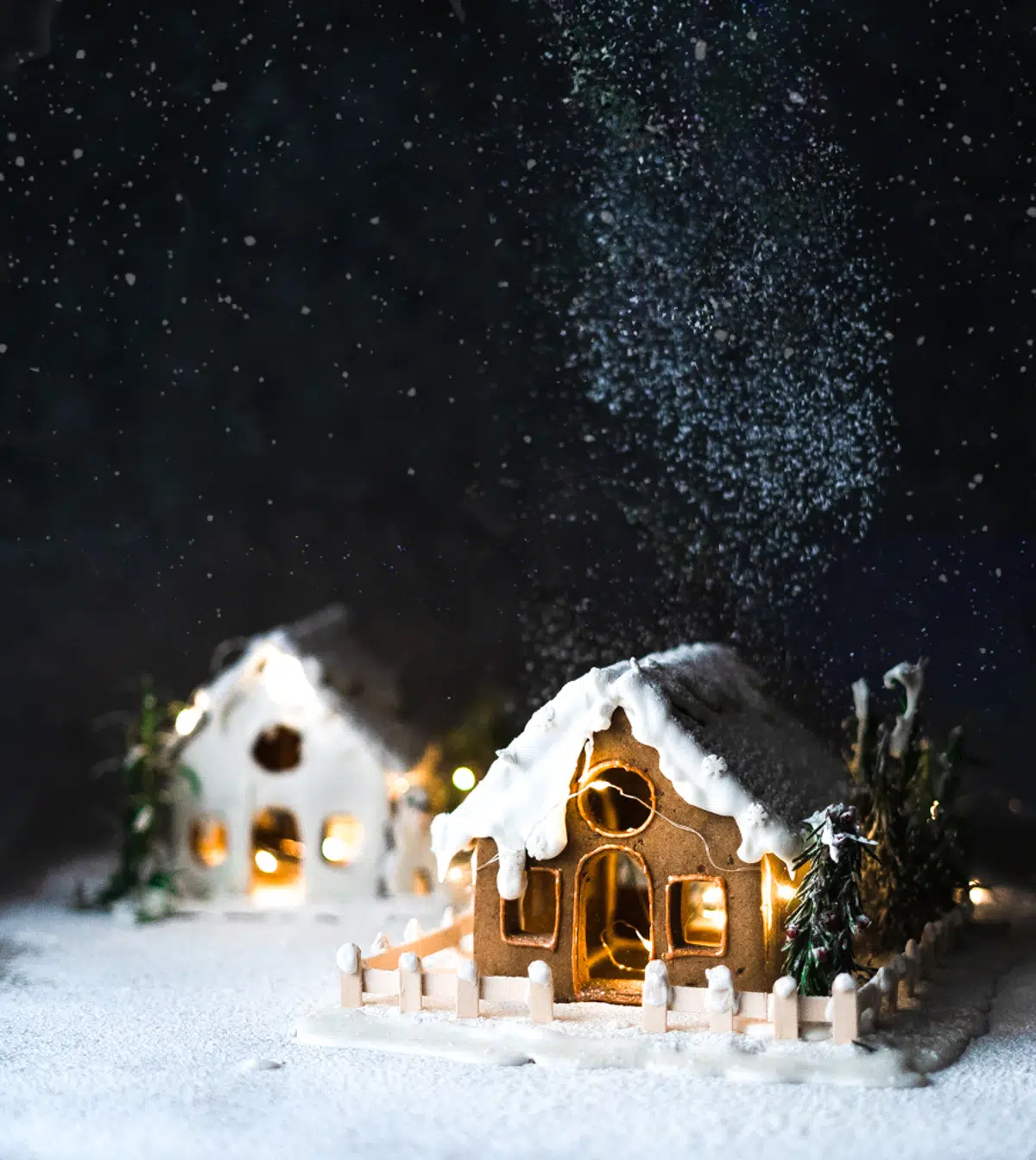 2 gingerbread houses with snow and dark background.