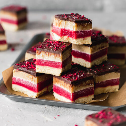 caramel slices with a bright fuchsia strip of raspberry jelly stacked on top of each other.