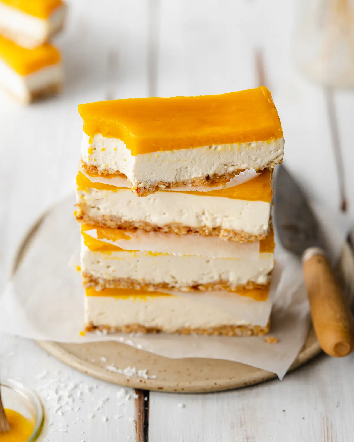 stack of mango cheesecake bars on a ceramic plate.