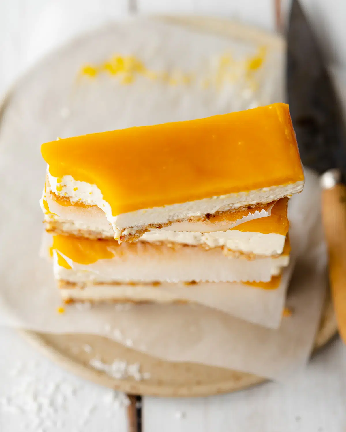 stack of mango cheesecake bars on a ceramic plate.