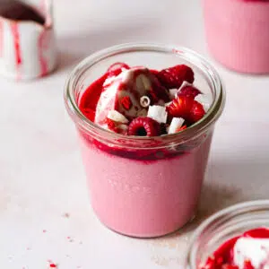 jar of raspberry mousse with cream and fresh raspberries.