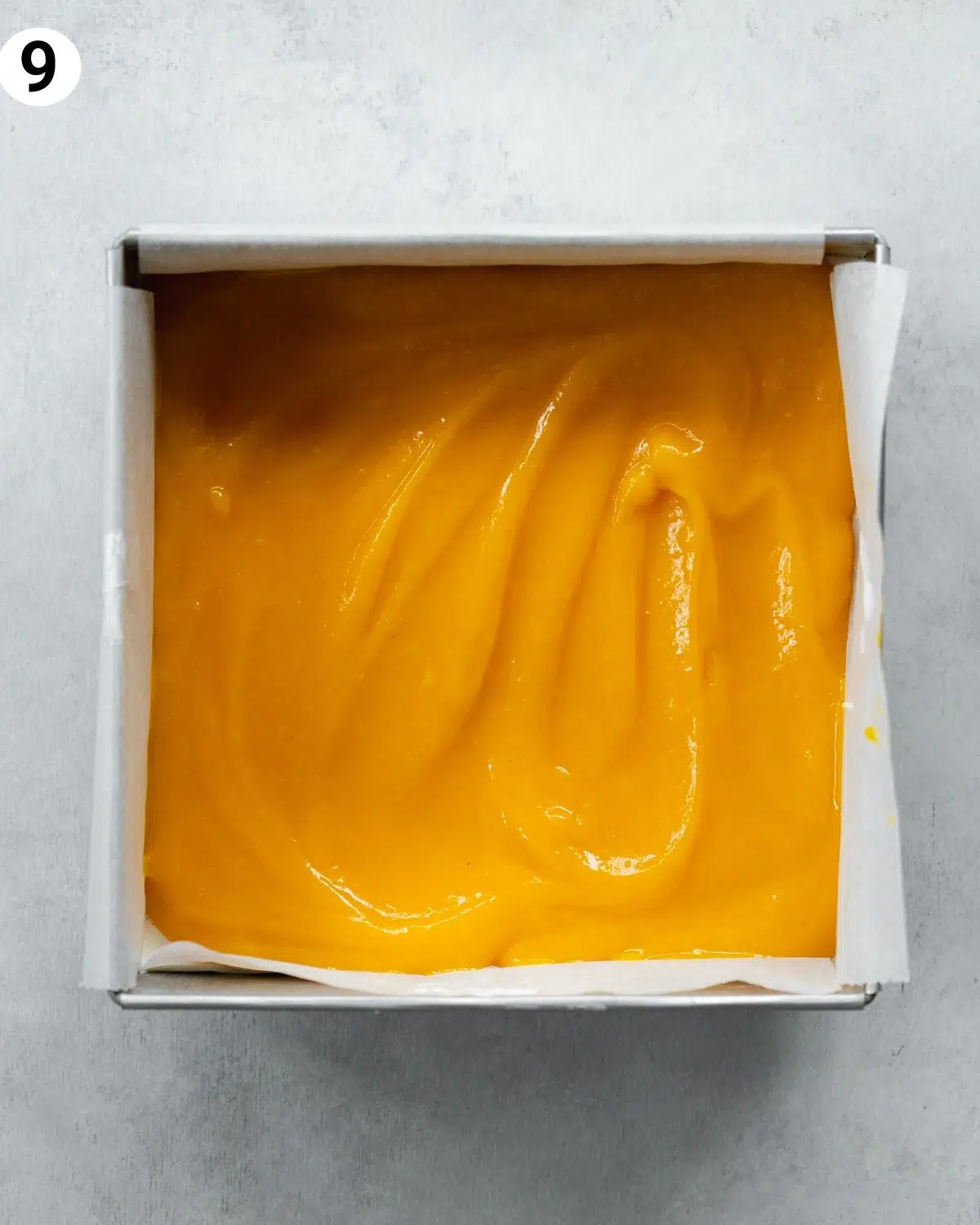 top down view of mango cheesecake in a square pan.