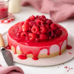 cheesecake with raspberry sauce and fresh raspberries on top.