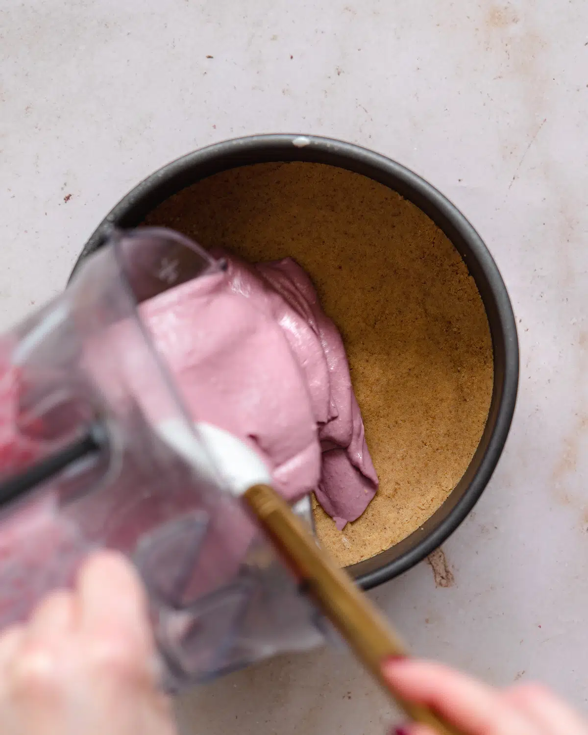 pouring raspberry cheesecake filing into cake pan.