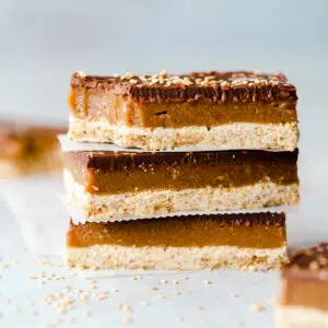 stack of tahini caramel bars on a blue surface.
