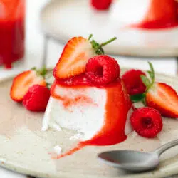 panna cotta with strawberry sauce pouring on top.