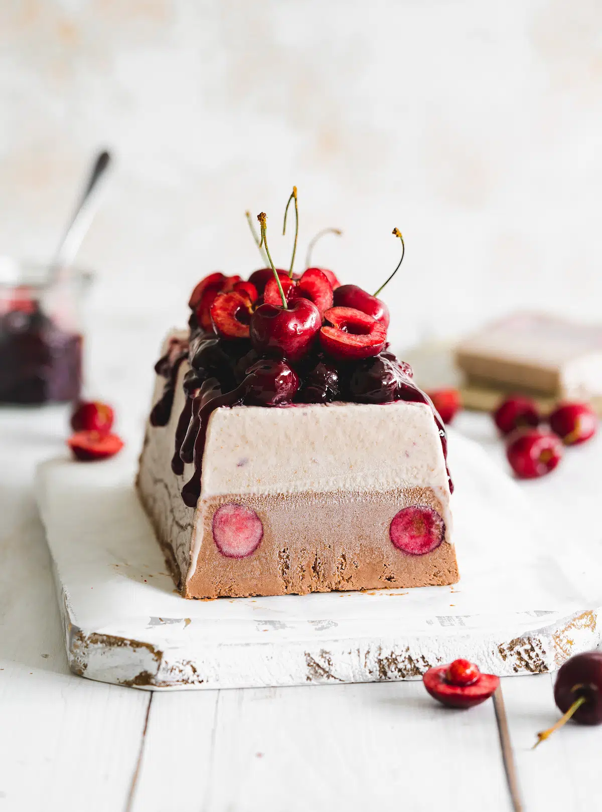 vegan chocolate cherry ice cream loaf on a white wooden board with white background