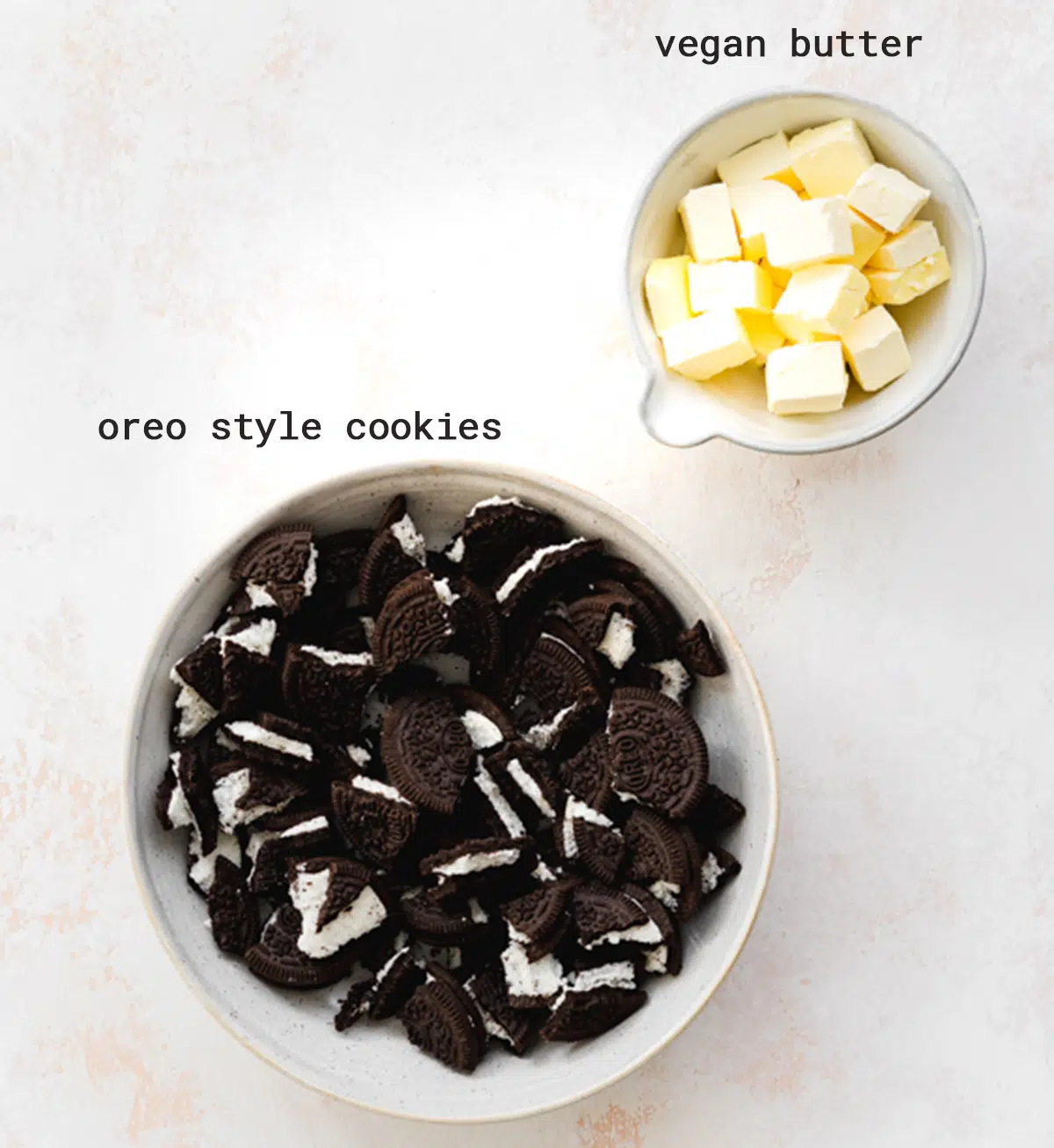 two bowls with oreo cookies and vegan butter on a flatlay peach stone surface
