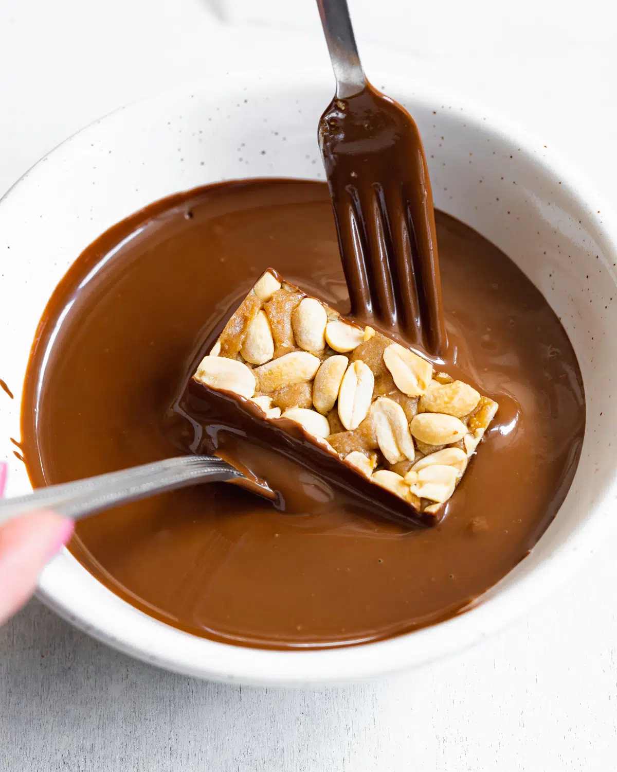 dipping homemade snickers bars in chocolate.