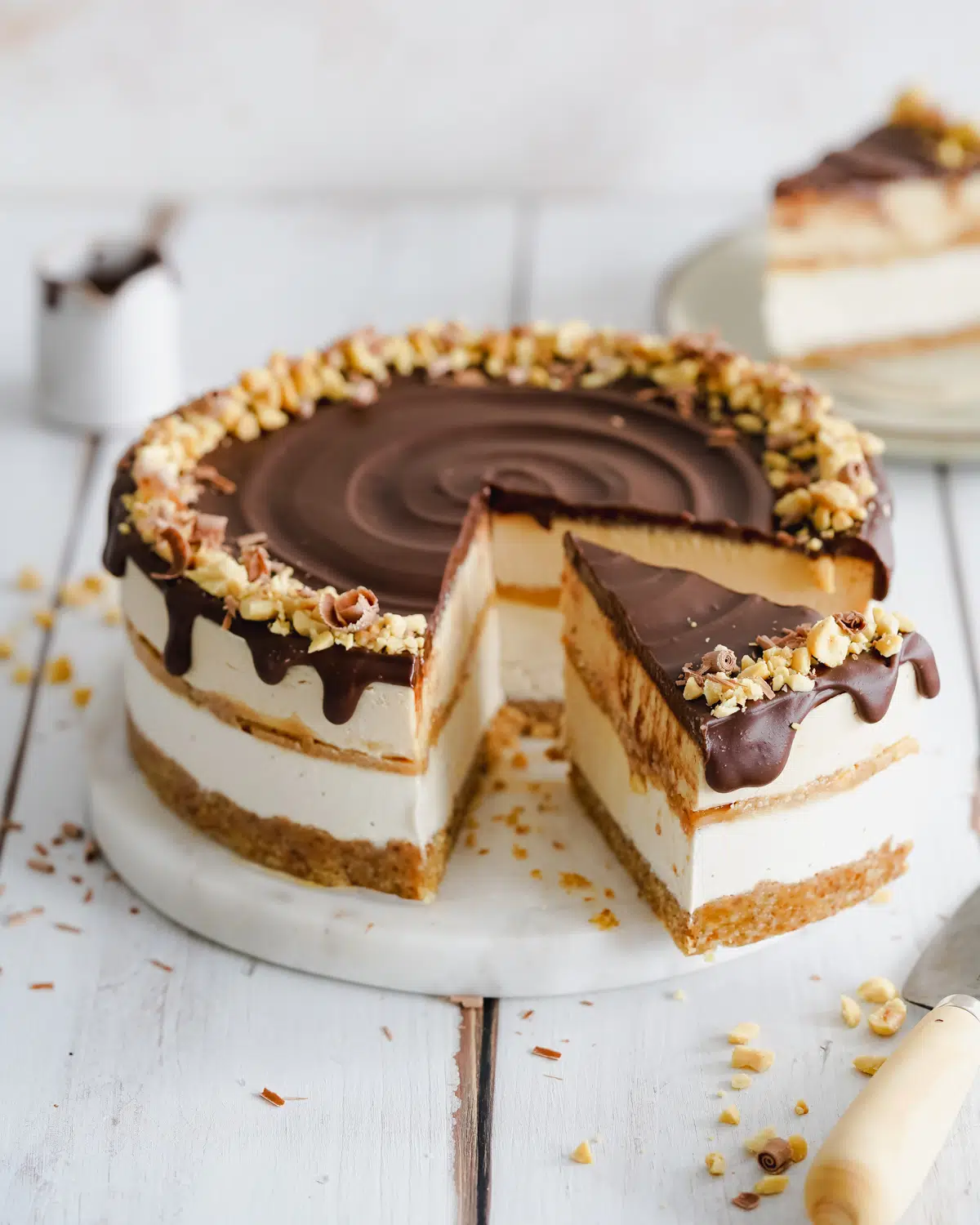 layered peanut butter chocolate cheesecake on white wooden cutting board.