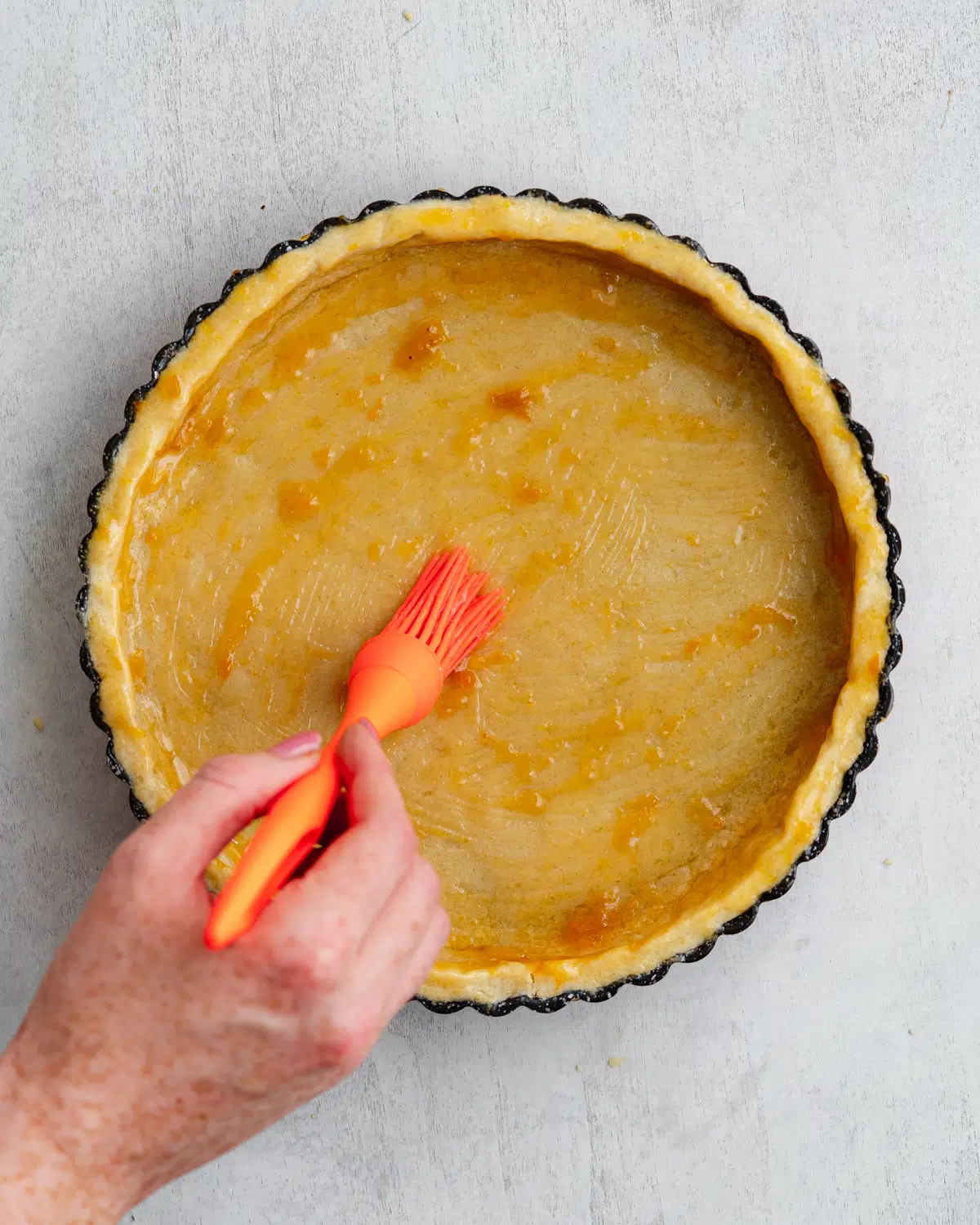 brushing shortcrust pastry with apricot glaze.