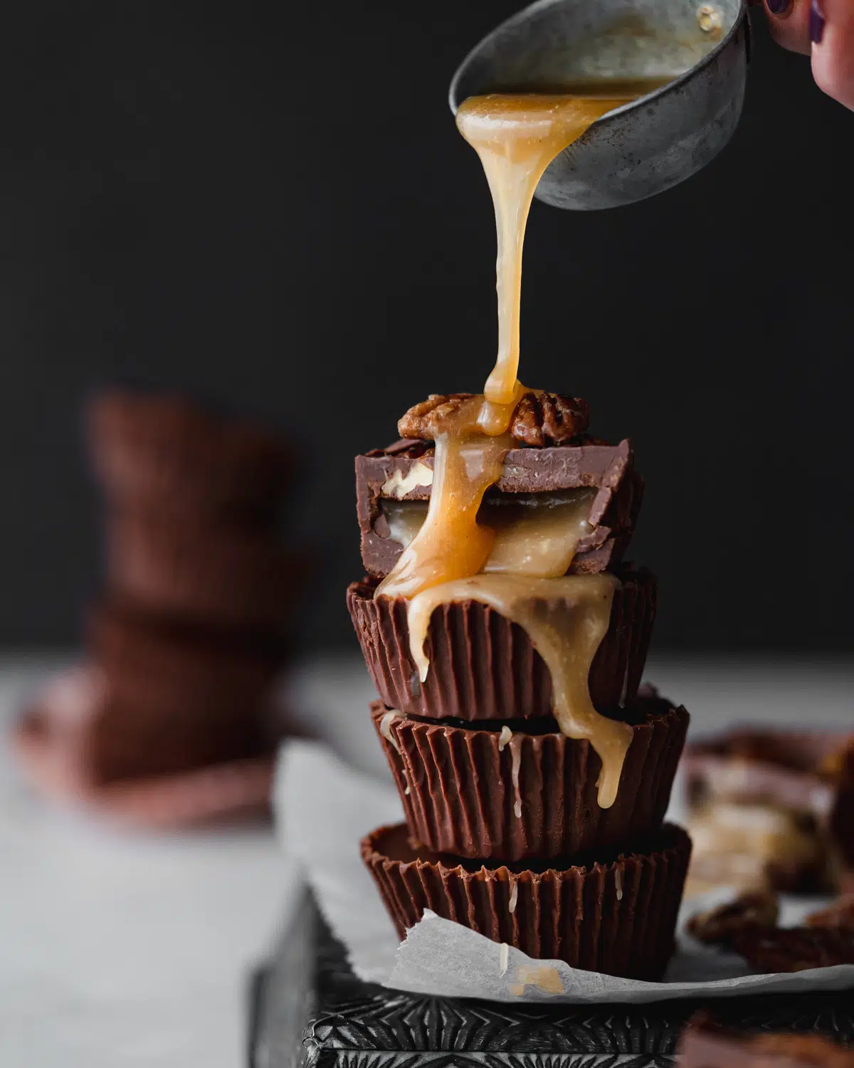 stack of maple caramel chocolate cups with caramel pouring on top.