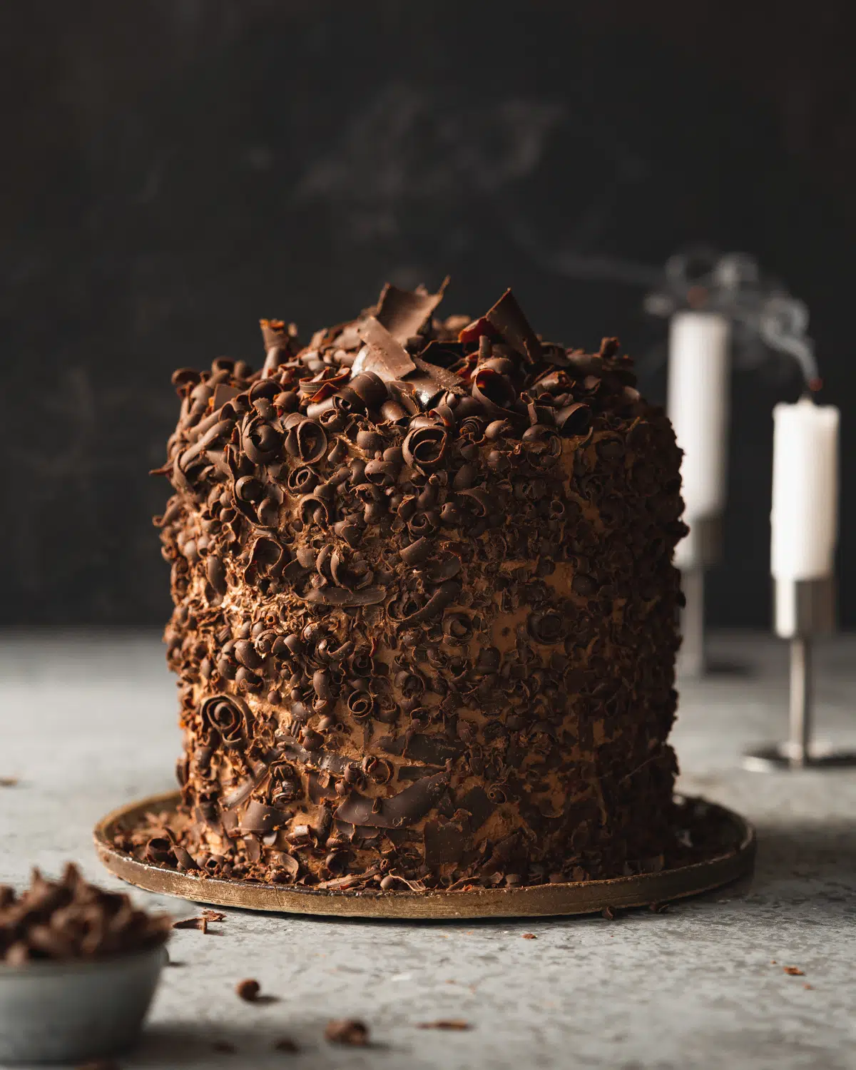 vegan chocolate cake with chocolate shavings and dark background.