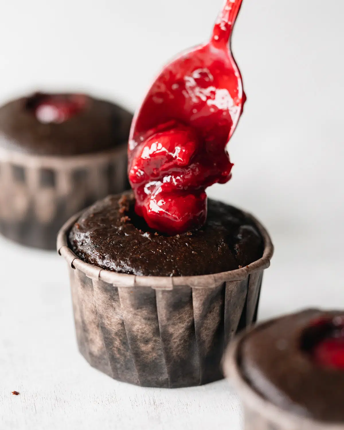 filling chocolate cupcakes with cherry sauce.