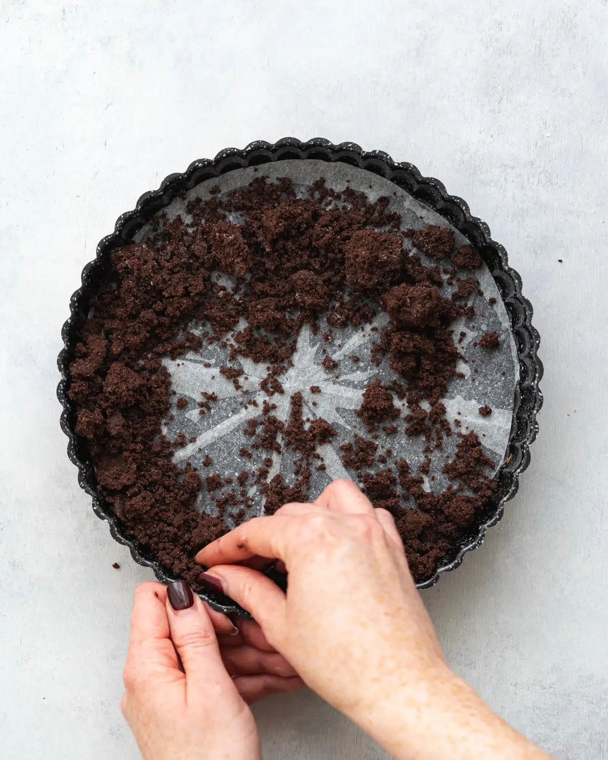 hands pressing chocolate shortcrust pastry into a tart tin.