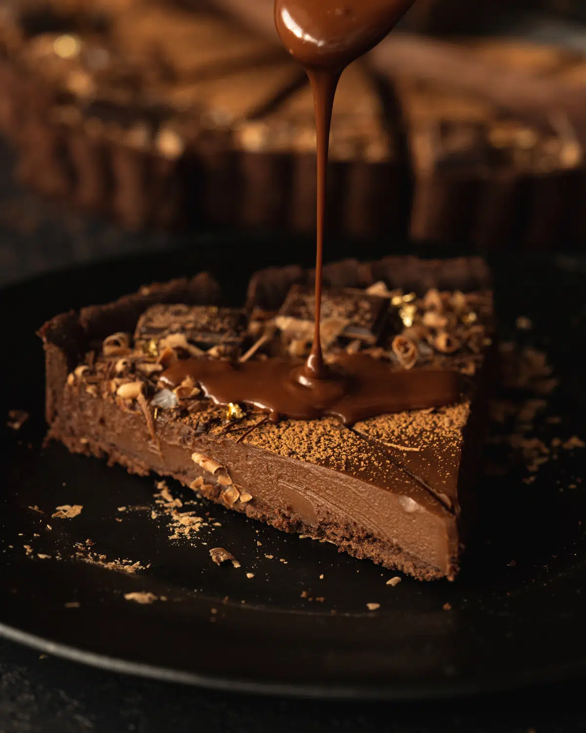 slice of double chocolate tart with chocolate ganache pouring over it.