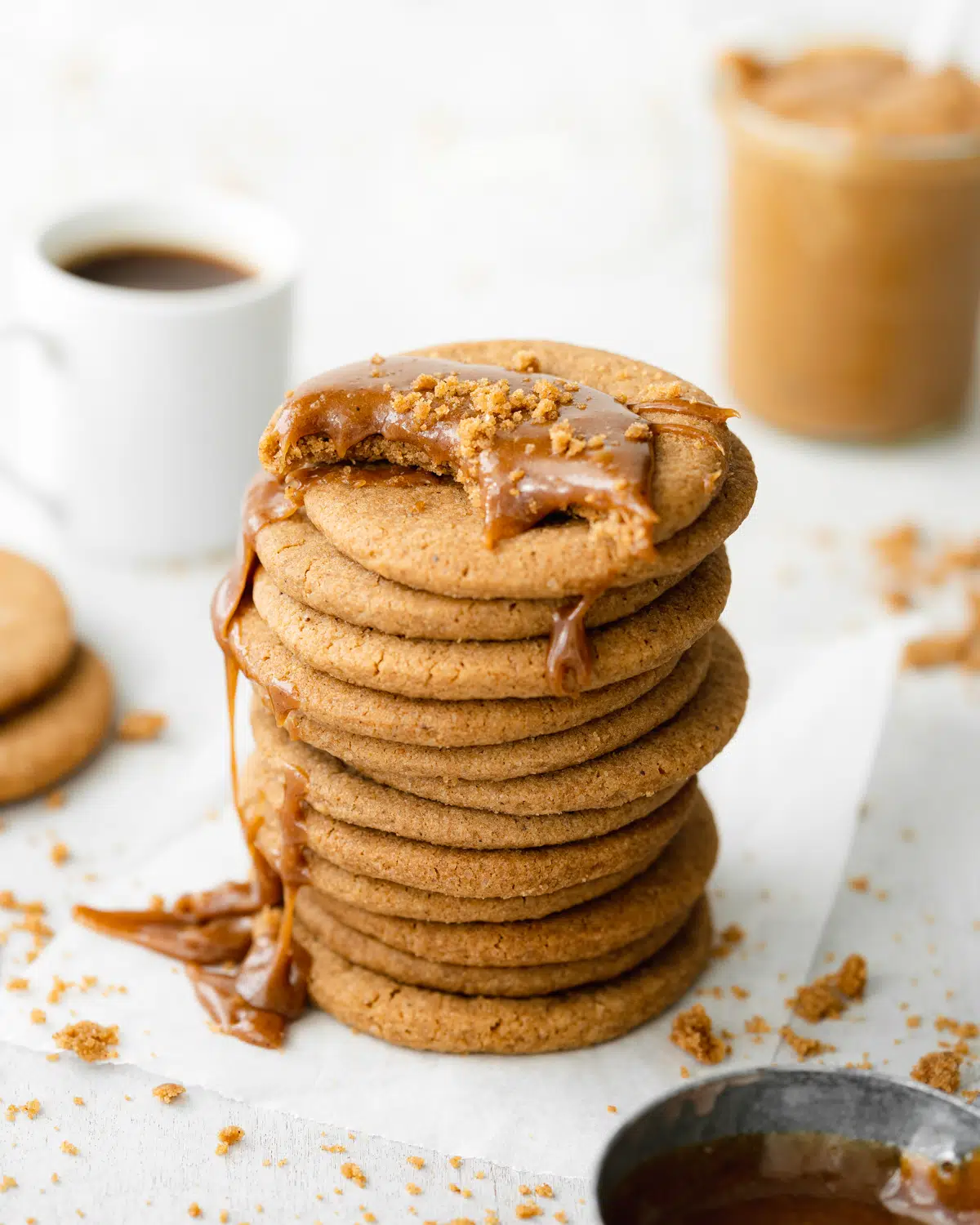 stack of homemade biscoff cookies with cookie butter spread on top and coffee in the background.