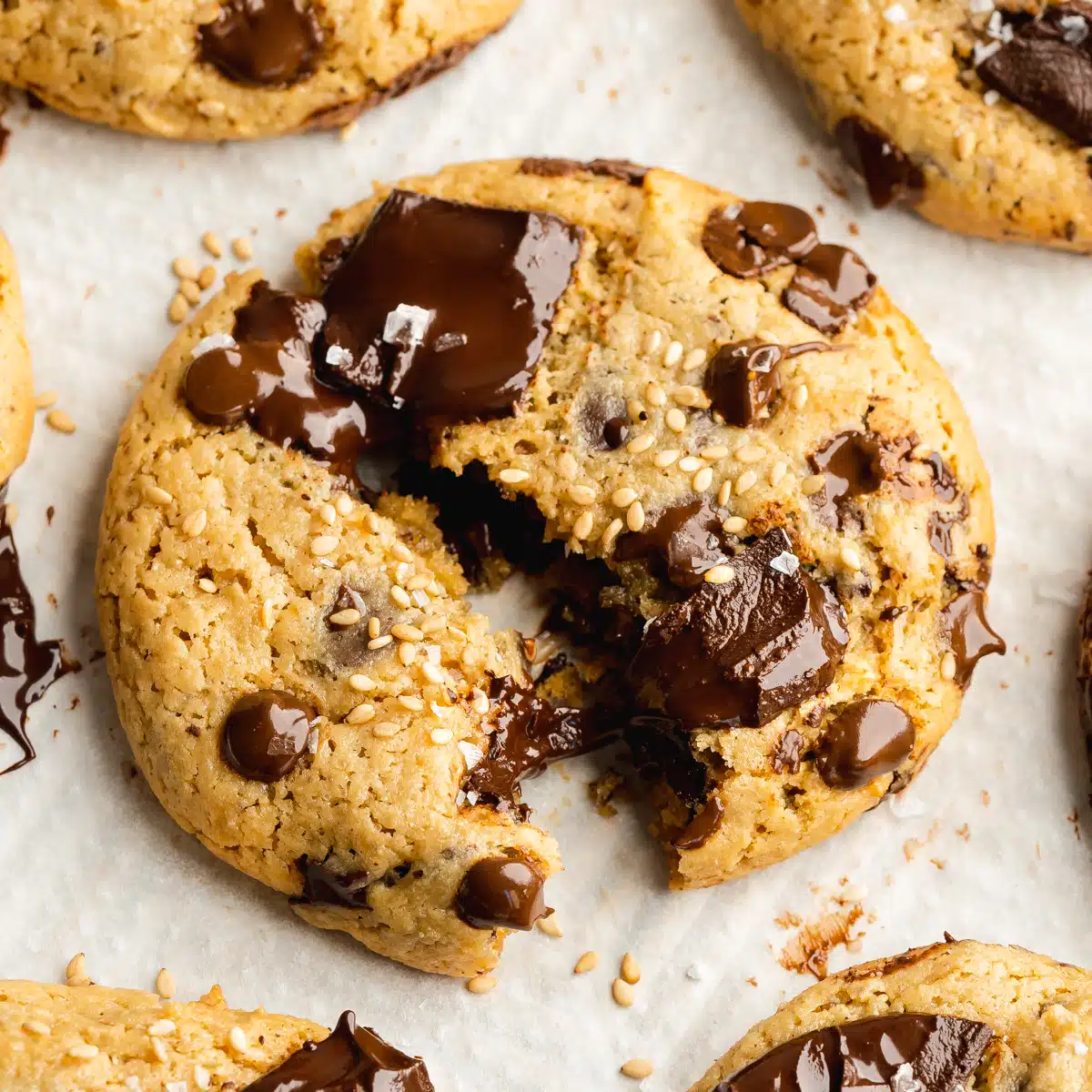 a tahini cookie with dark chocolate chunks that are melted and toasted sesame seeds on top.