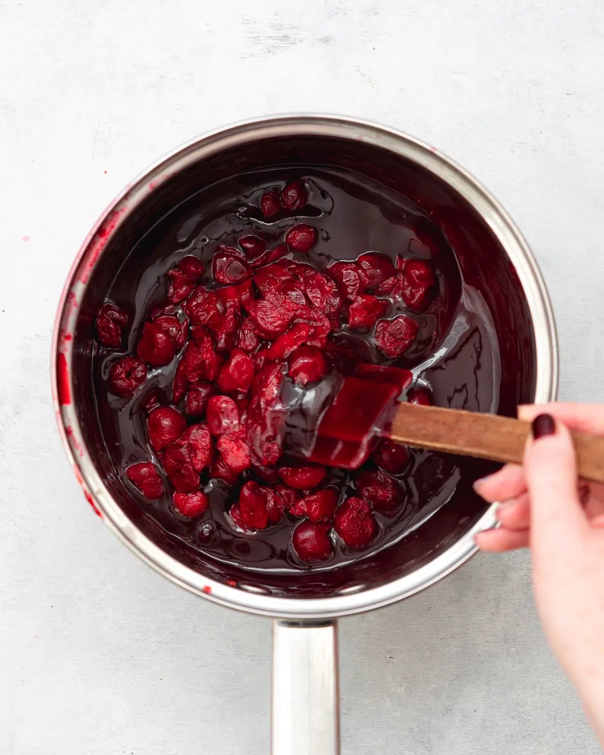 stirring cherries into cherry sauce.