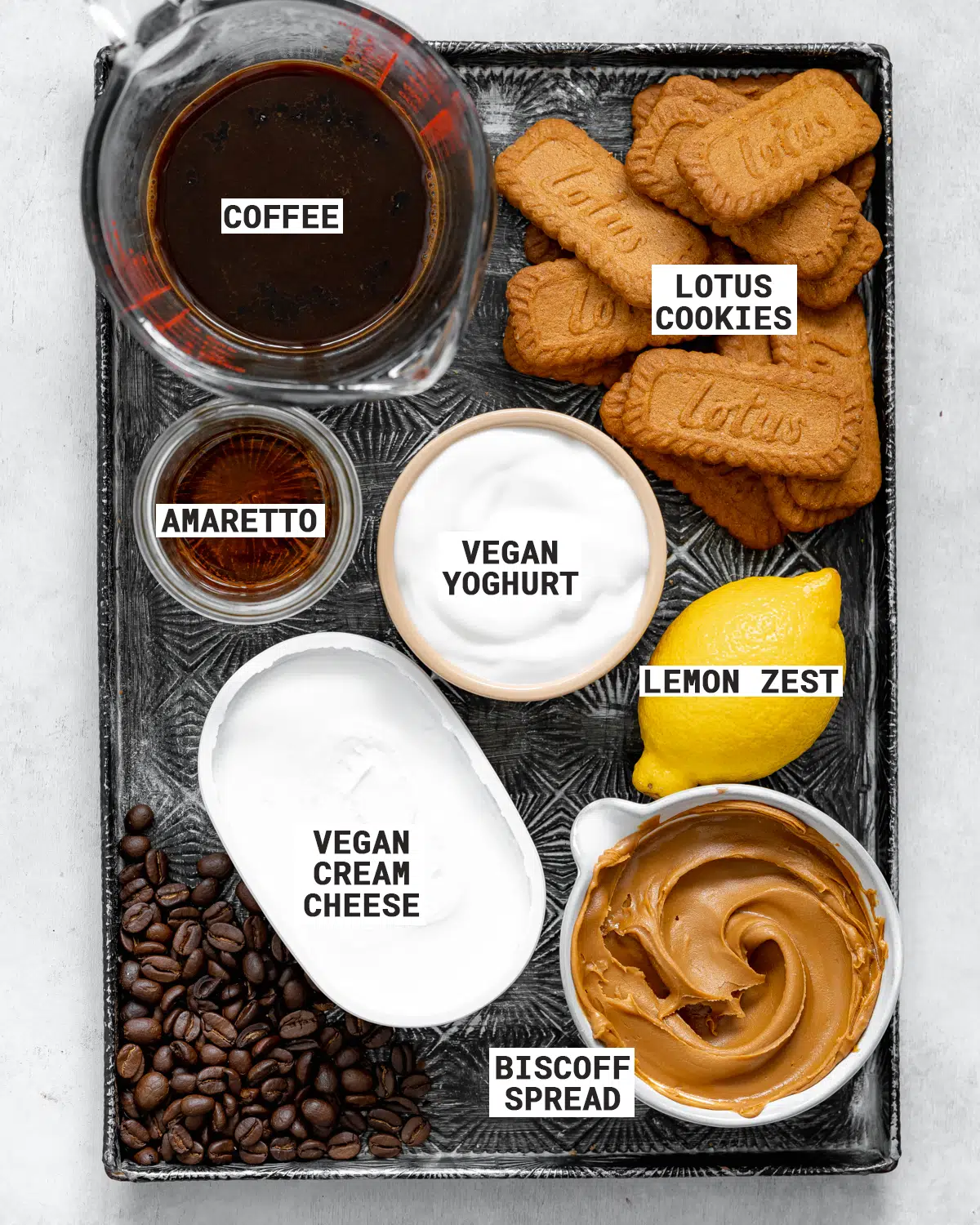 ingredients for making vegan tiramisu with biscoff cookies on a metal tray.