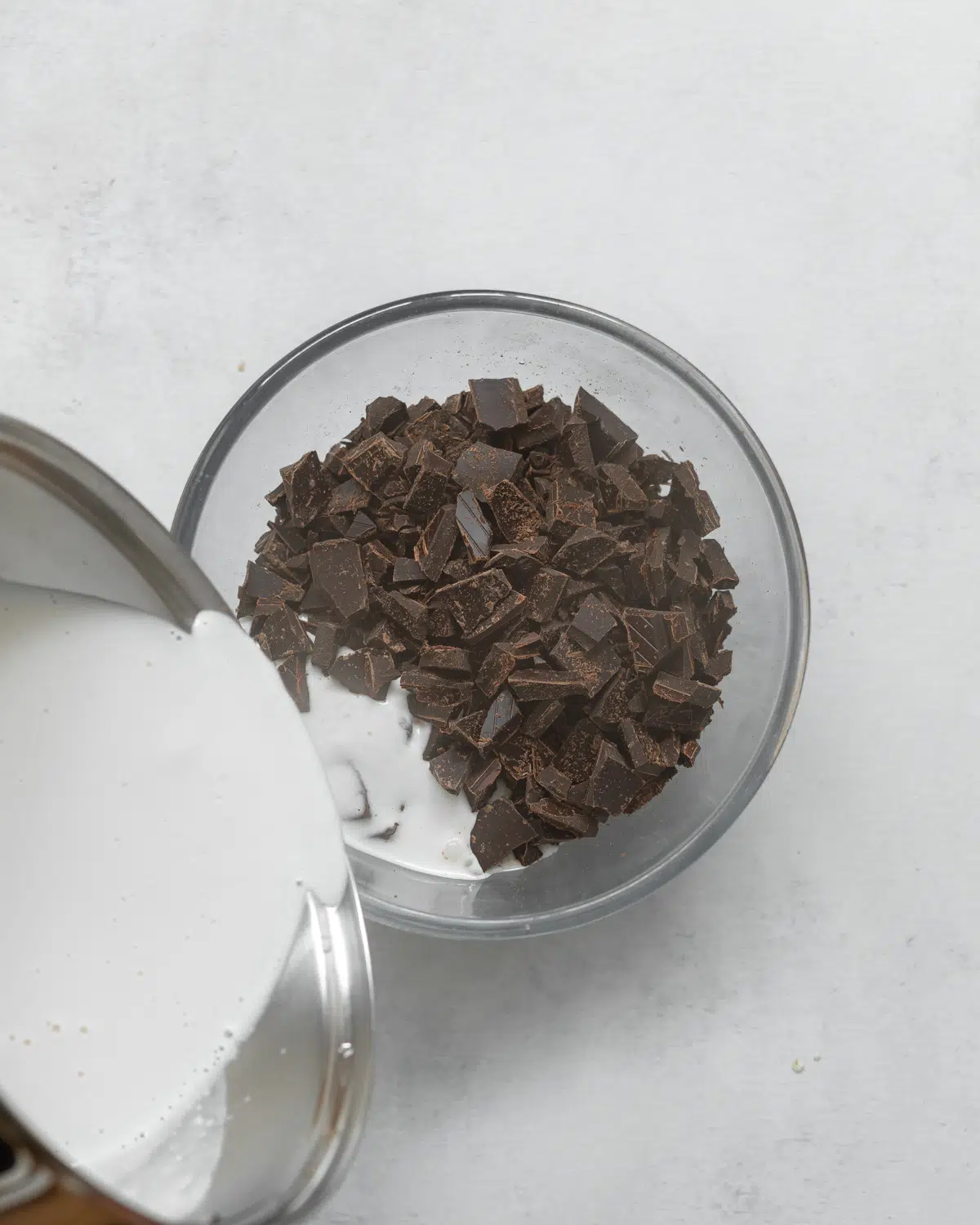 pouring hot coconut milk into chopped chocolate.
