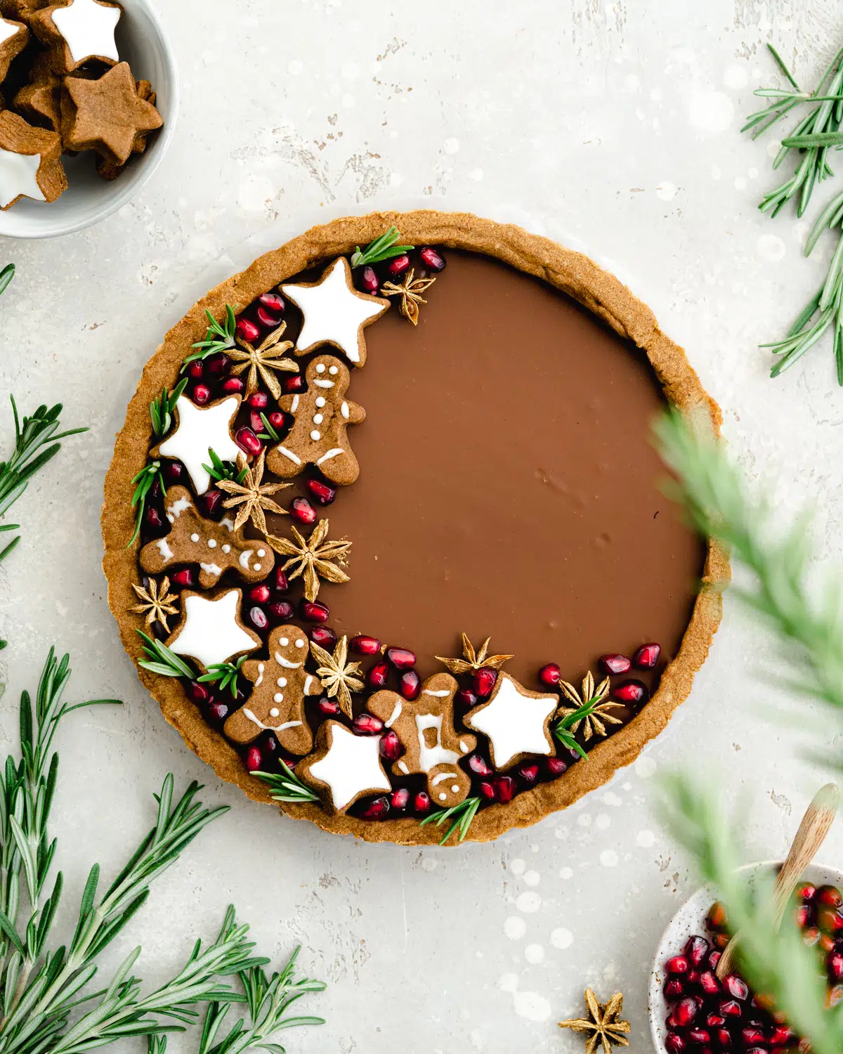 chocolate tart with gingerbread cookies and pomegranate seeds on top.