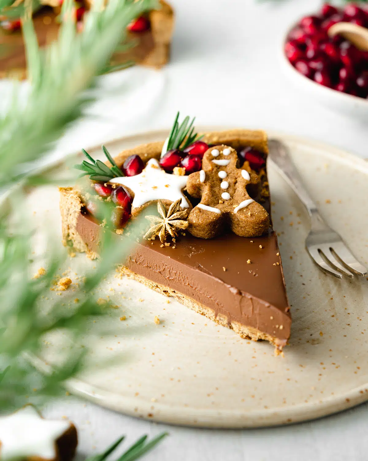 chocolate tart with gingerbread and evergreen leaves in the foreground.