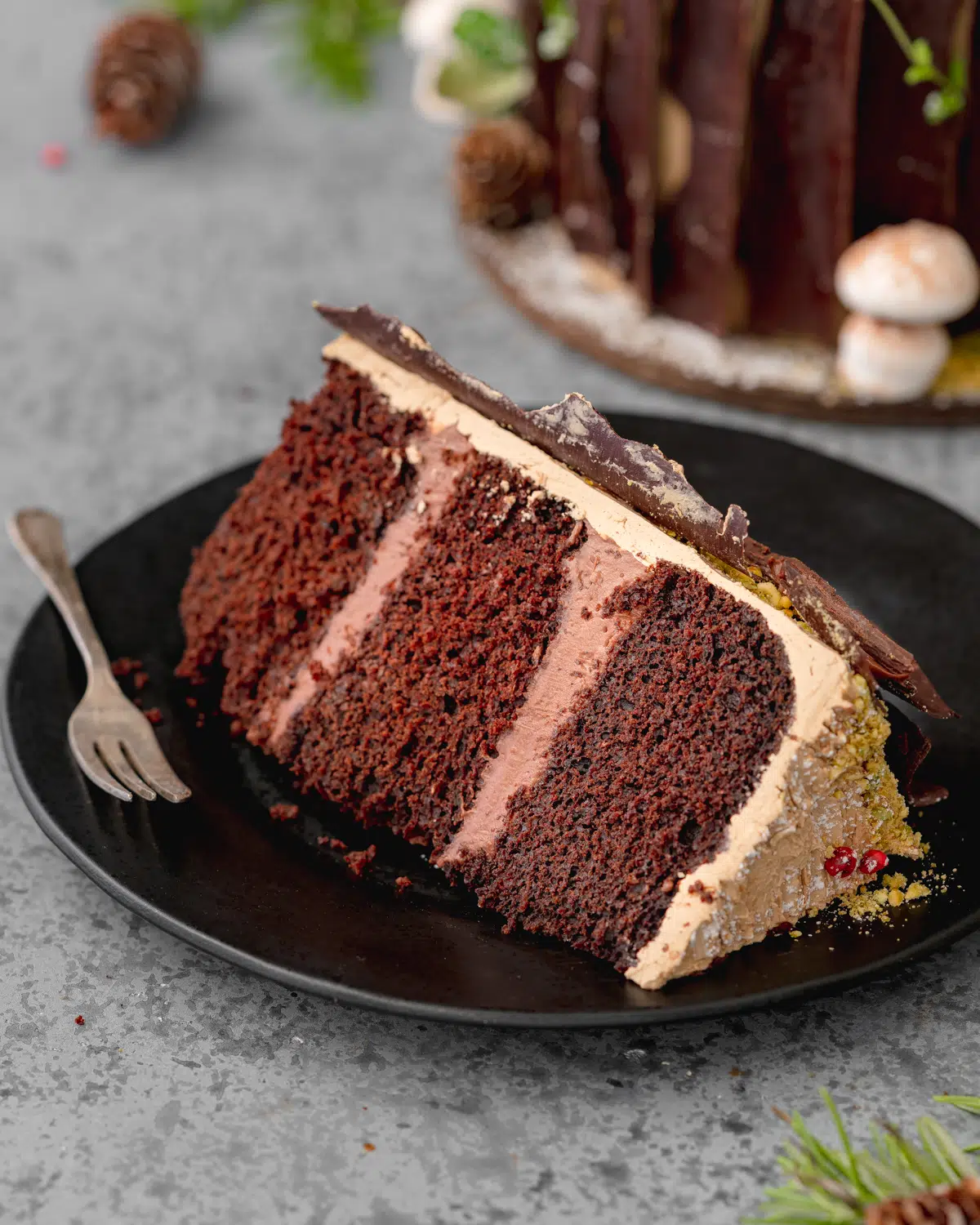 slice of layered vegan chocolate cake on a black plate.