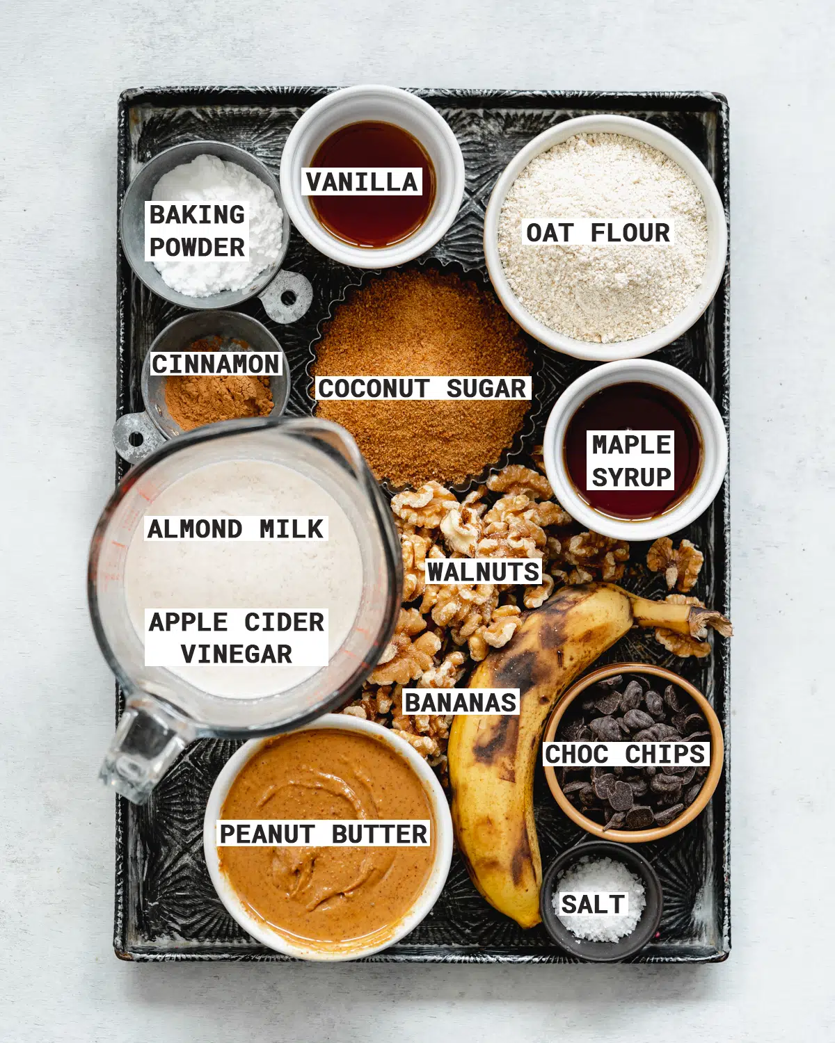 ingredients to make vegan chocolate chip banana muffins on a metal tray.