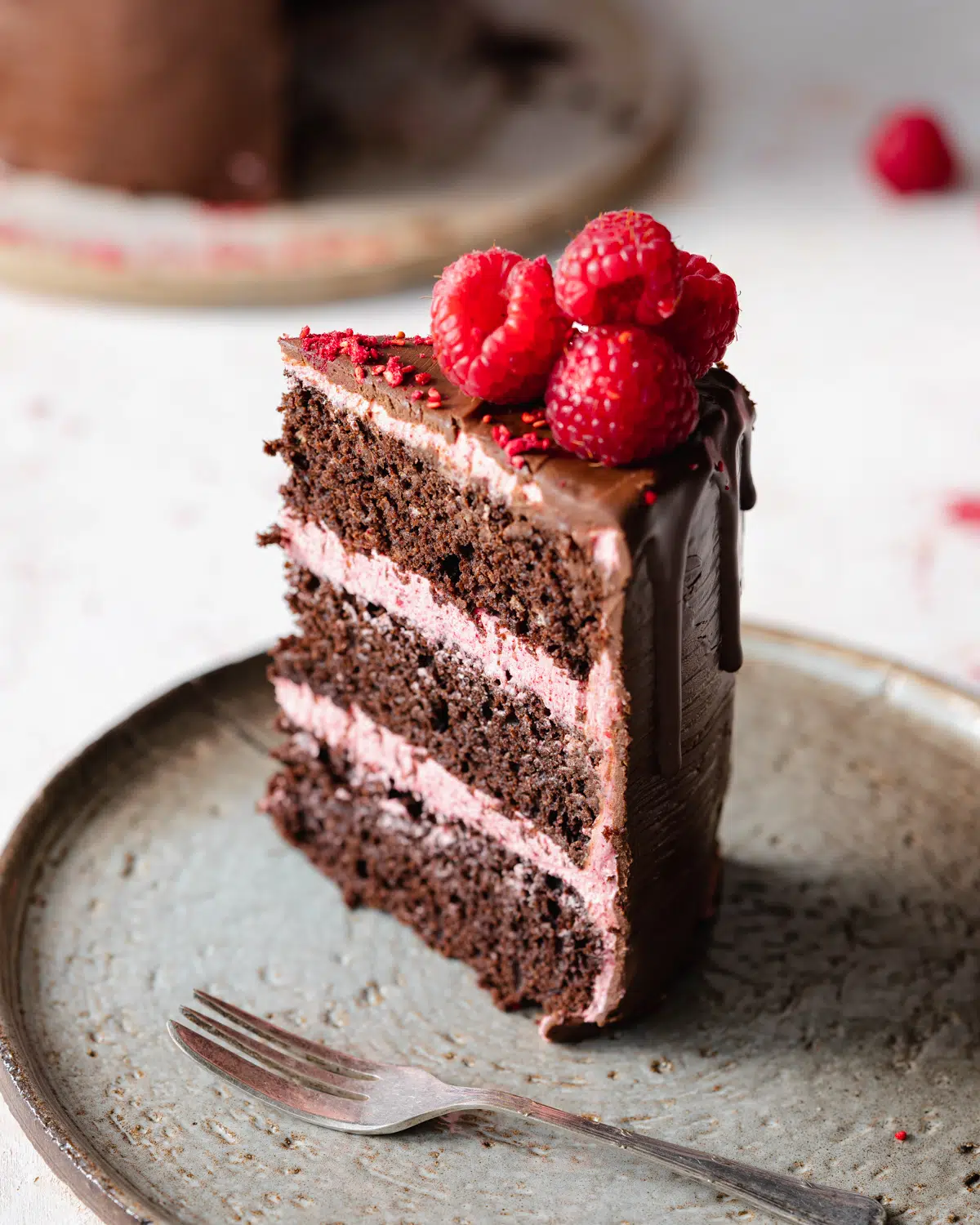 slice of eggless chocolate cake with raspberry buttercream and ganache.