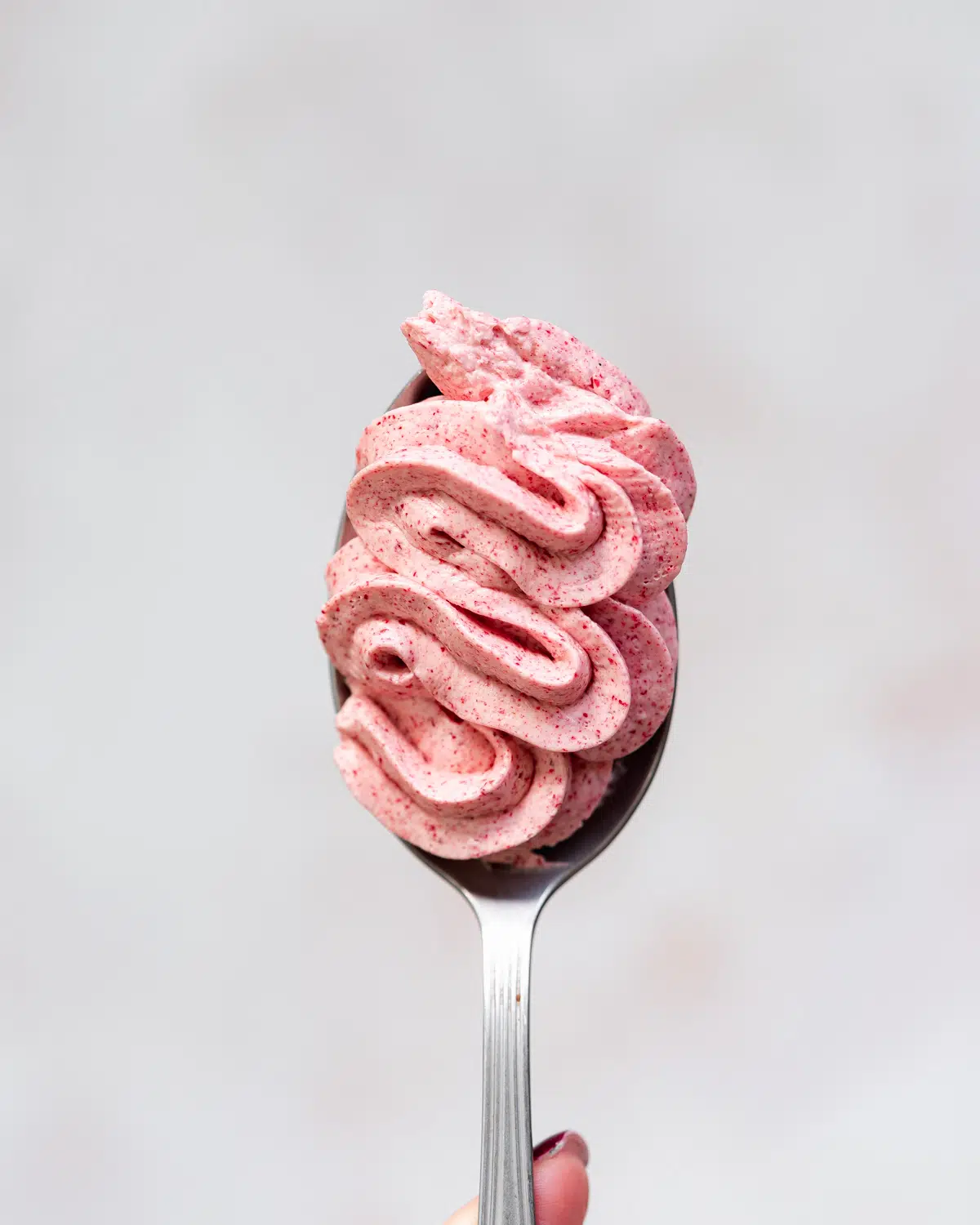 dairy-free raspberry buttercream on a spoon.